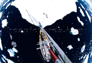 A sailboat anchors on an ice sheet while its crew explores. Located in  the west coast of Antarcticas peninsula known as Graham Land.