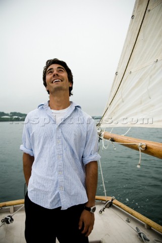 Man looking up at sails on sailboat Casco Bay Maine New England releasecode rausher and rausherPR