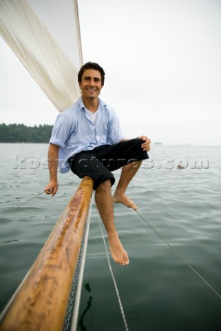 Man smiling on bowsprit of sailboat Casco Bay Maine New England releasecode rausher and rausherPR