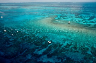 Both privately owned and commercial dive boats appear tethered to  mooring buoys on Molasses Reef, Key Largo, Florida.  This aerial view provides a prospective of the spur and groove type of coral formation typical in the Florida Keys, wherein the coral formations are separated by large sand channels.  Nearby  unmanned Molasses Reef Light marks a shallow area of the reef and also serves as a collection point for marine observations collected as data for NOAA.