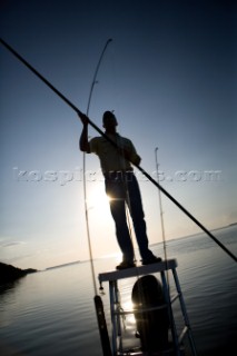 A flats boat captain poles through shallow water in the Everglades while silhouetted by the sun at dawn. Chris Ross/Aurora Photos/Kos Pictures