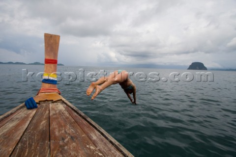 Female in bikini takes a plunge off of a longtail boat in Thailand