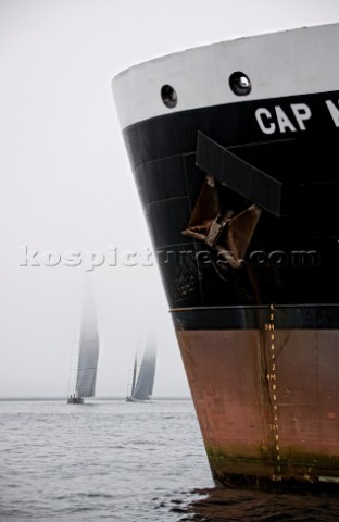 J Class fleet racing in Falmouth 2012 past the bow of a commercial ship